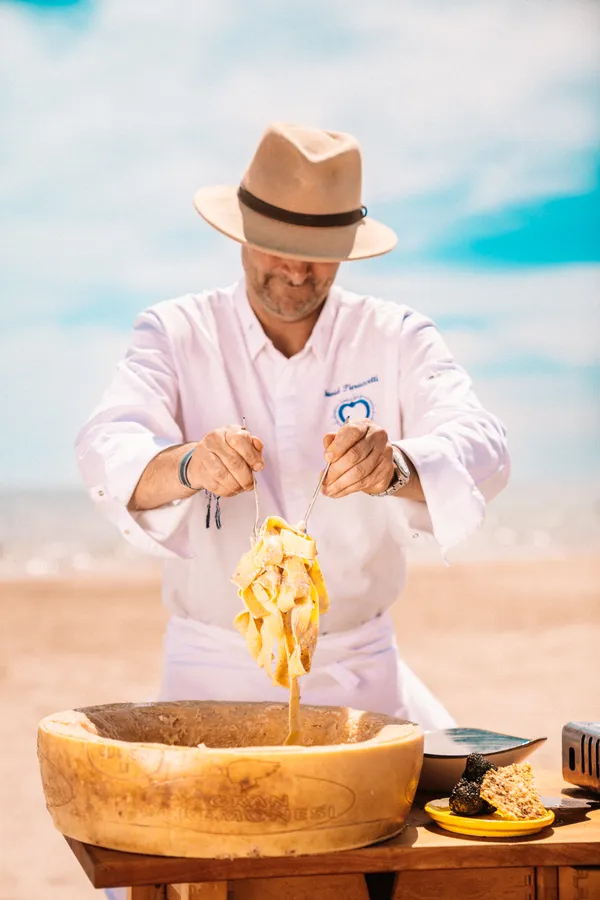 Chef servant des pâtes dans une meule de parmesan à La Voile Bleue