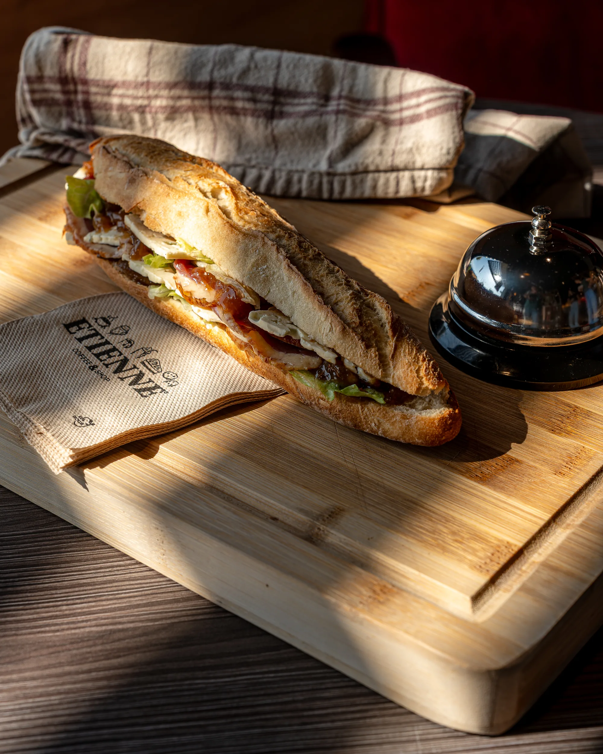 Sandwich sur une planche avec le papier Étienne Coffee & Shop et une sonnette de comptoir