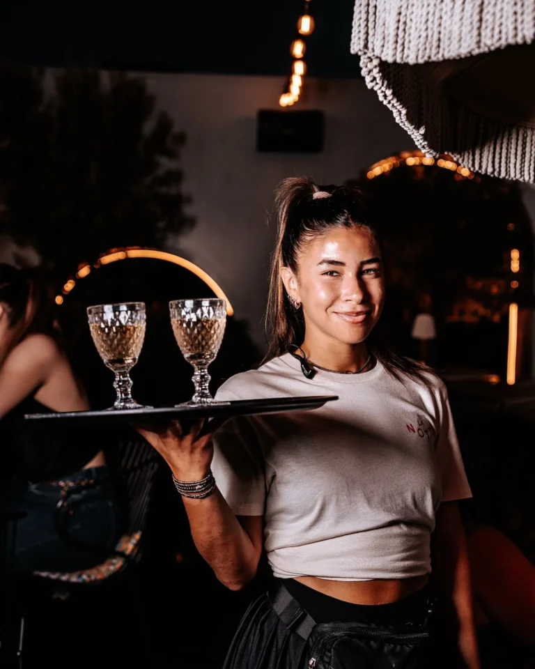 Serveuse souriante avec des coupes sur un plateau à La Notte