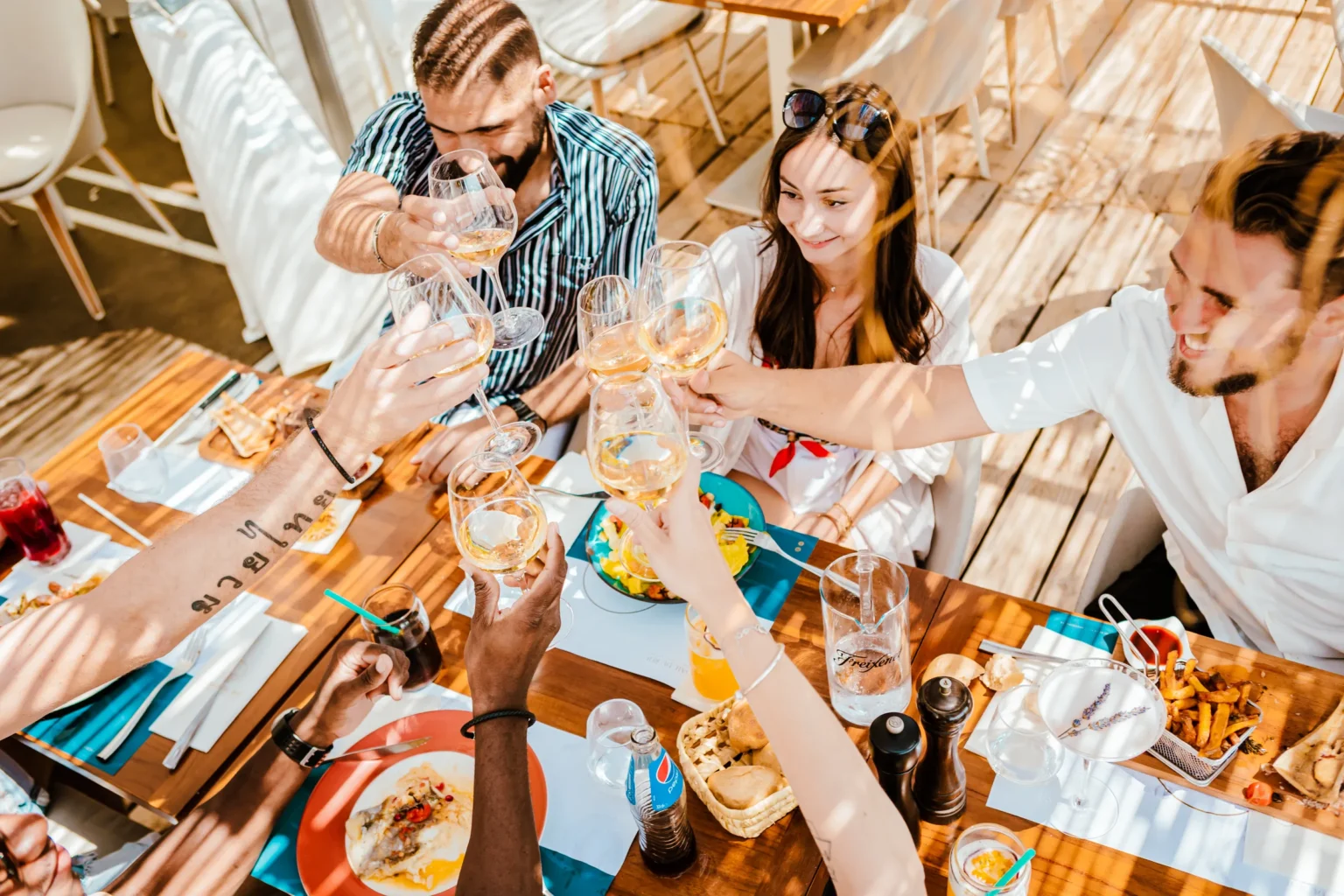 Amis qui trinquent à table à La Baie du Roi, plage privée