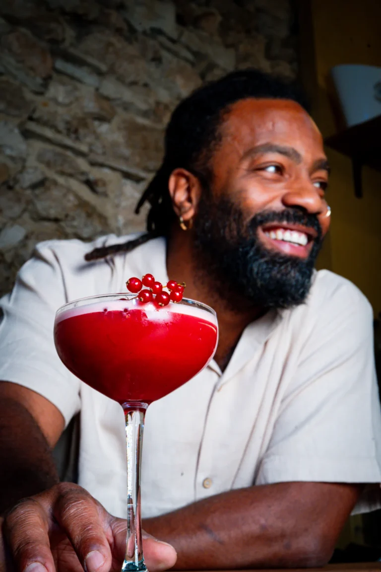 Barman souriant avec un cocktail rouge aux groseilles