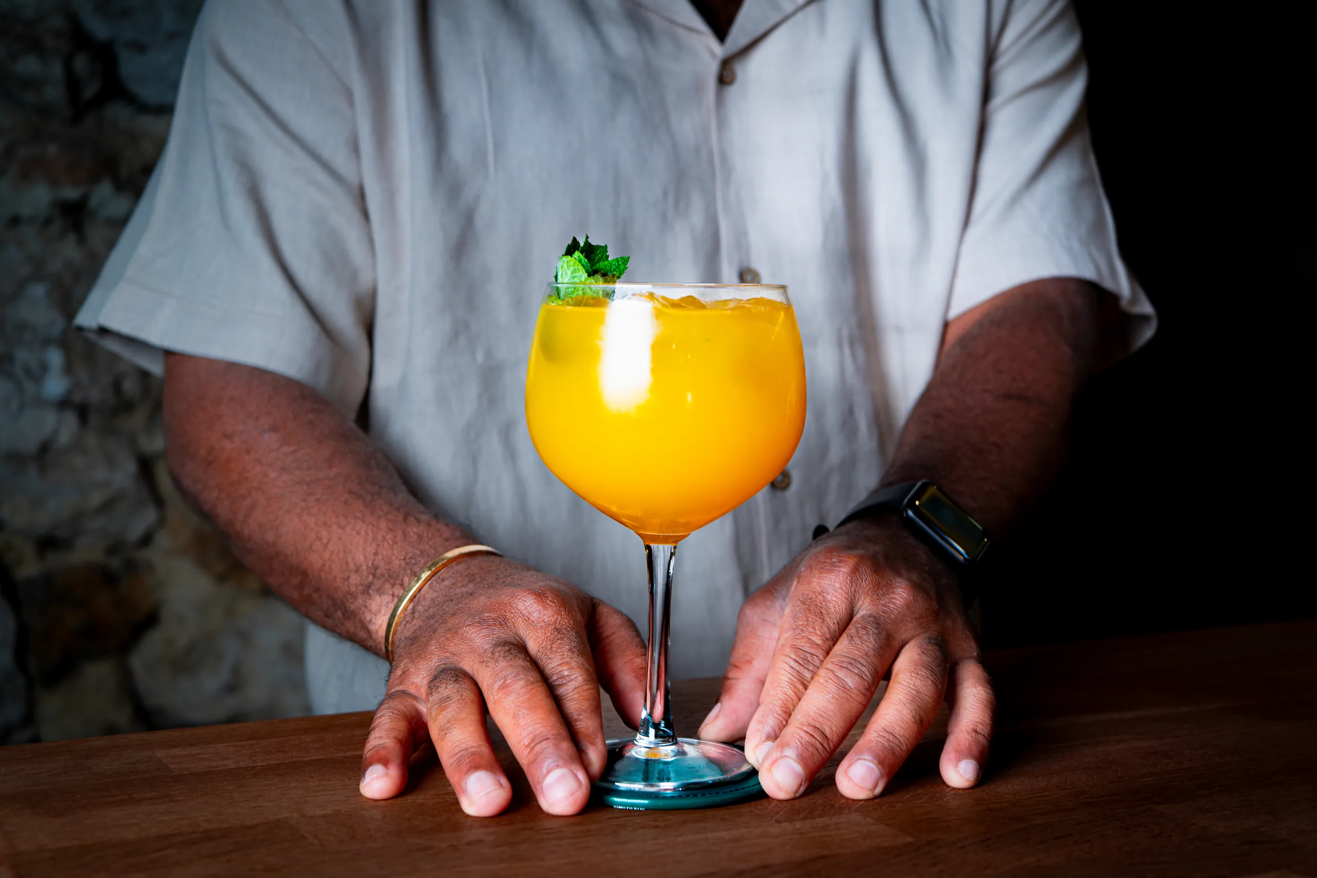 Barman de La Bonne Dose qui présente un cocktail orange