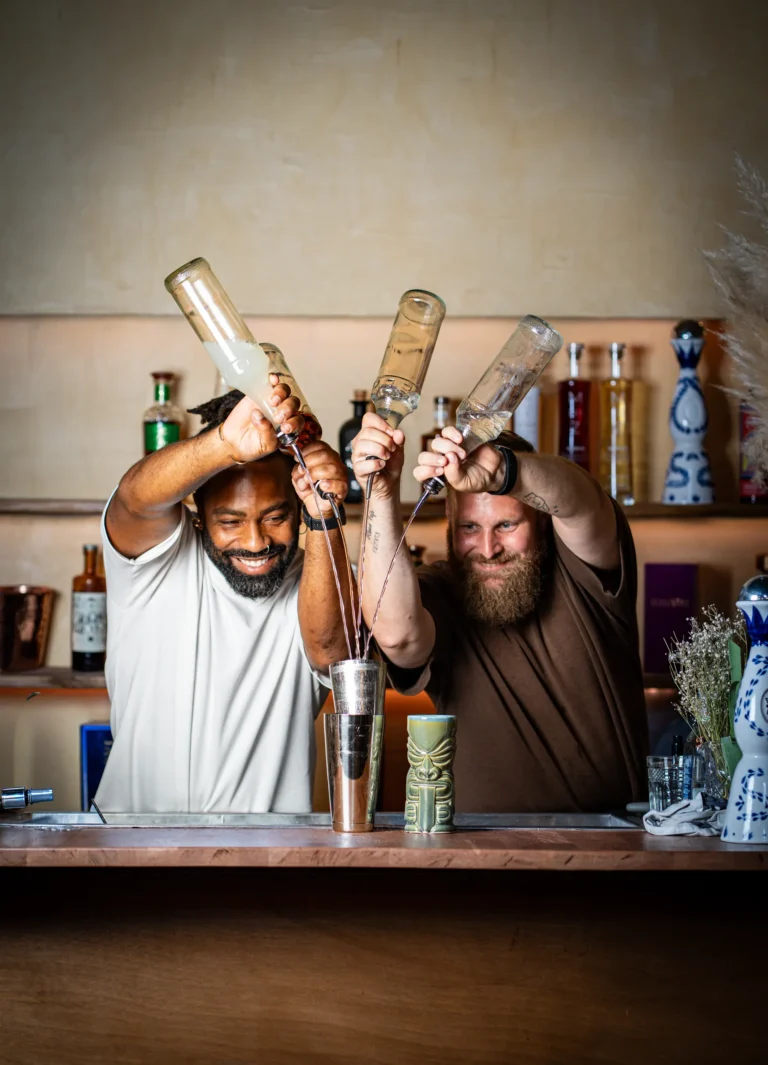 Deux barmen de La Bonne Dose versent leurs bouteilles